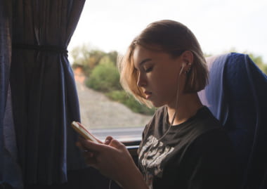 a woman uses her phone while sitting in a charter bus seat